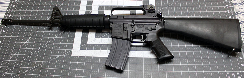 left side view of a Colt AR-15 Lightweight rifle, lying on a crafting mat for scale